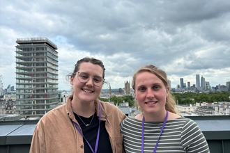 Ellena and Alice on the rooftop terrace at The Crown Estate office, with the London skyline behind them